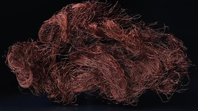 Thin, twisted, and chaotically tangled copper wire against the backdrop of an industrial interior, abstract metallic from non ferrous metals in a factory environment
