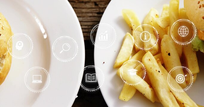 Displaying white plates with seasoned fries and burger buns, lettuce on dark table, digital icons