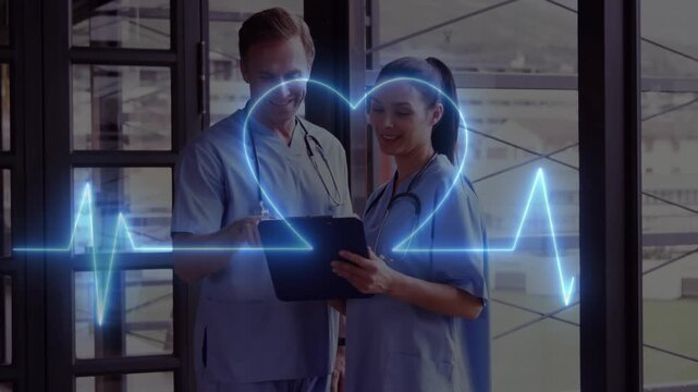 Medical team reviewing records on clipboard at window ECG entering left aligning it into heart