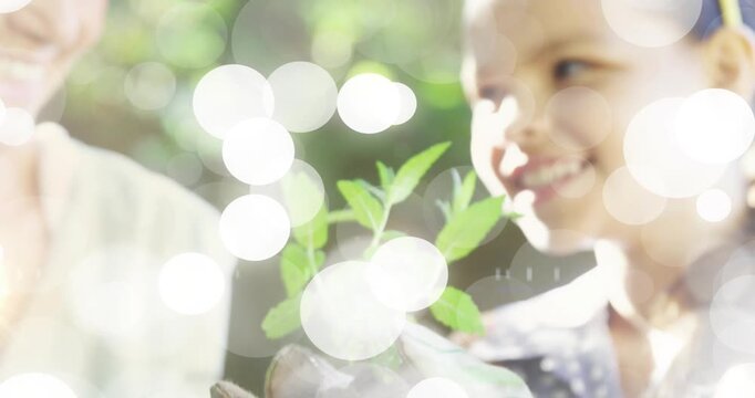 Child and elder woman holding seedling, lifting seedling causing bokeh flares gardening lesson