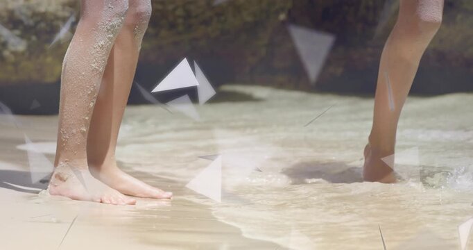 Two girls playing lifting foot creating splash toward feet, triangles drifting over feet for design