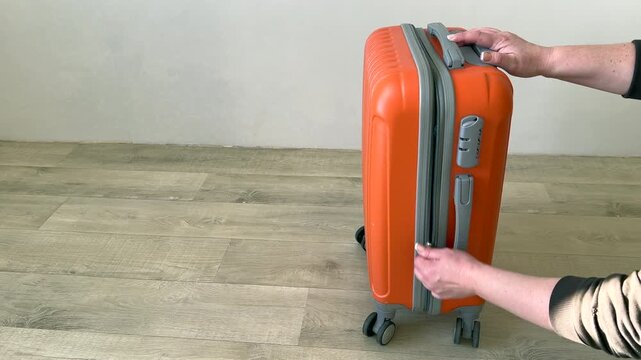Woman struggling to close an overpacked suitcase