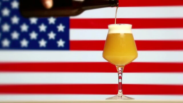A hazy craft beer being poured into a Teku glass with an American flag background.
