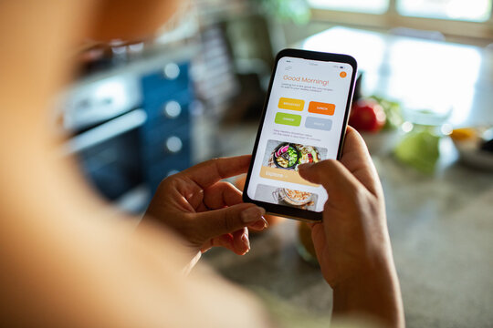 Person using recipe app on smartphone in home kitchen