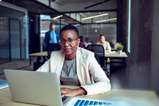 Confident businesswoman working on laptop in modern open plan office