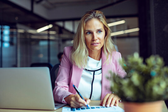 Businesswoman analyzing data and reports at laptop in modern office