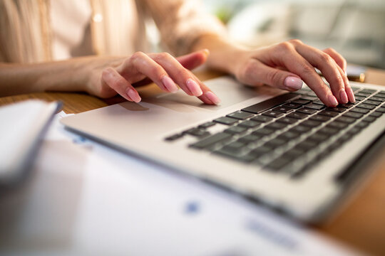 Woman typing on laptop at home office desk