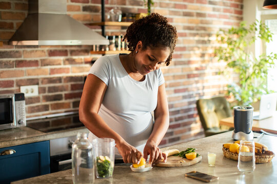 Smiling woman making fresh smoothie in home kitchen
