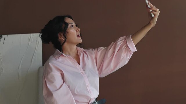 A young Asian woman, blogger, or video caller, speaks into a phone camera.