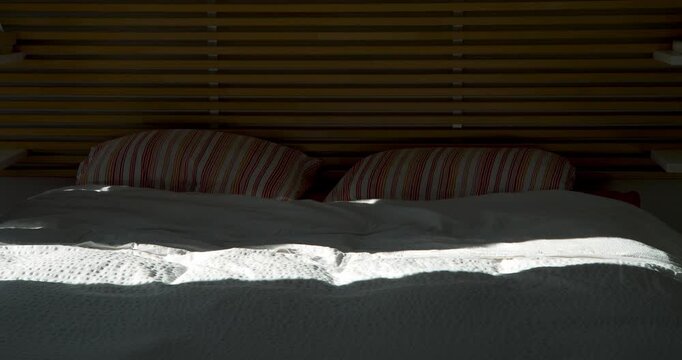 Restful Sanctuary: A tranquil bedroom scene showcasing the epitome of relaxation. Soft light bathes a neatly made bed adorned with pillows and plush bedding.