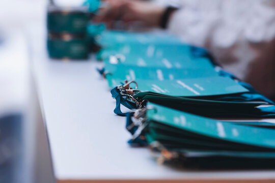 Registration desk table at conference, checking in congress forum event, visitors and attendees register electronic ticket and receiving blue lanyard with blue name badge and entry wristband bracelet