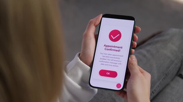 Woman receives appointment confirmation on smartphone after booking beauty salon online. Close-up of mobile screen with success message. Perfect for lifestyle, online booking, self-care, beauty