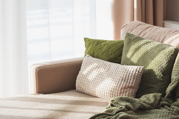 Fototapeta premium Textured Pillows and Blanket on Sofa. Cozy Spring Home Interior with Natural Light