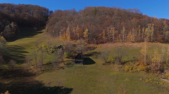 Cinematic Approach to Traditional Wooden Barns on Scenic Sunny Autumn Hillside under Forest in Poiana Marului Zarnesti Drone Flight 4K Graded
