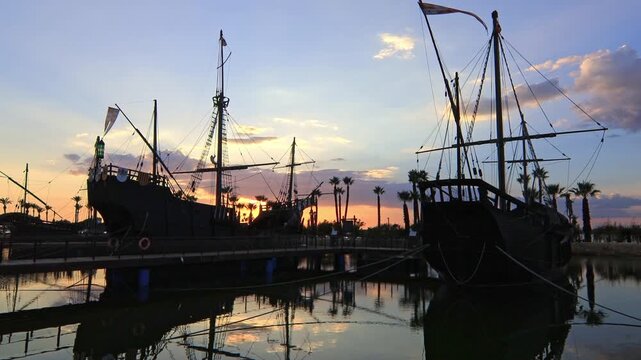 Historic replicas of the Pinta, Nina, and Santa Maria caravels at Muelle de las Carabelas, Huelva, Spain, during a colorful sunset. Ideal for travel and history content