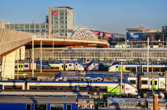 Saint-Denis, France - December 29, 2025: Numerous SNCF regional trains parked at the railway yard, with the modern Franchissement Urbain Pleyel bridge and SNCF Group headquarters in near Paris