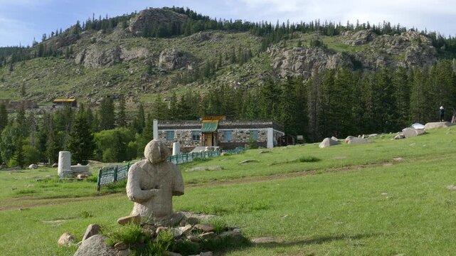 A stone woman (Kurgan stelae) on a clearing against the backdrop of a rocky mountain .Mongolia, summer sunny day.
