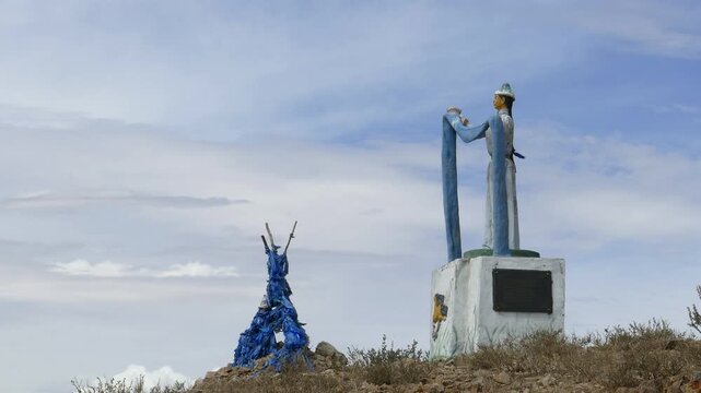 Sacred pile of stones (ovoo, oboo) and sculpture women c with a scarf in their hands against the backdrop of a picturesque cloudy sky.