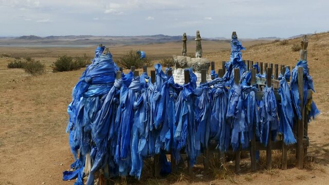 Santmargats, MONGOLIA - July 18, 2017. The Mongolian man turns the prayer wheels next to the Buddhist stupa in the steppe.
