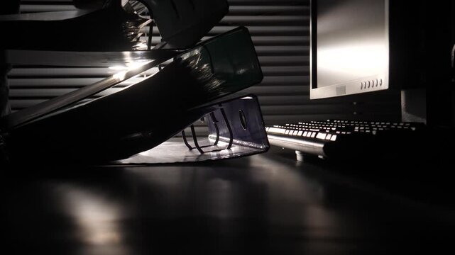 Stacked binders and documents on a shadowy desk next to a glowing computer monitor and keyboard in a dim office, conveying concepts of late night work, investigation, and business secrecy