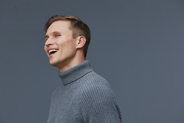 Fototapeta premium Smiling caucasian man wearing gray turtleneck sweater looking away happy casual portrait studio background digital detox mental health concept