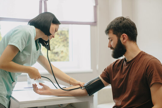 Nurse checking man's blood pressure in clinic