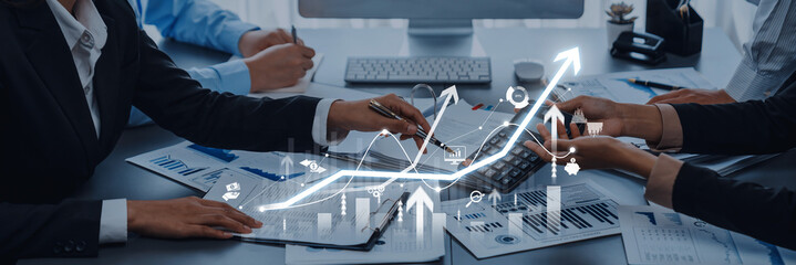 Modern business team collaborates to analyze financial data with digital graphs, showcasing growth and strategy in a professional office environment. Trope