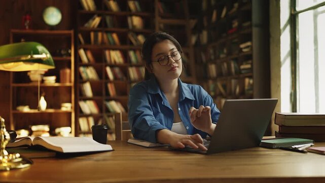 Korean woman finishing project and closing laptop in library, satisfied