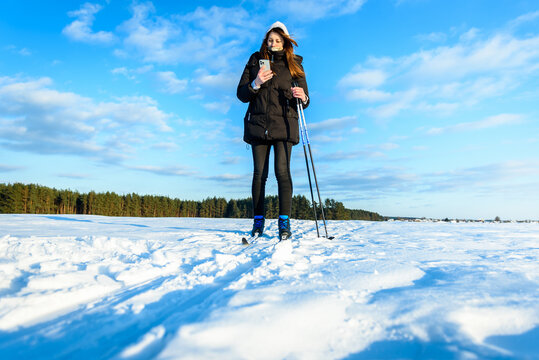Skier on cross-country skis in the snow on forest trail of the sun above the horizon in winter.
