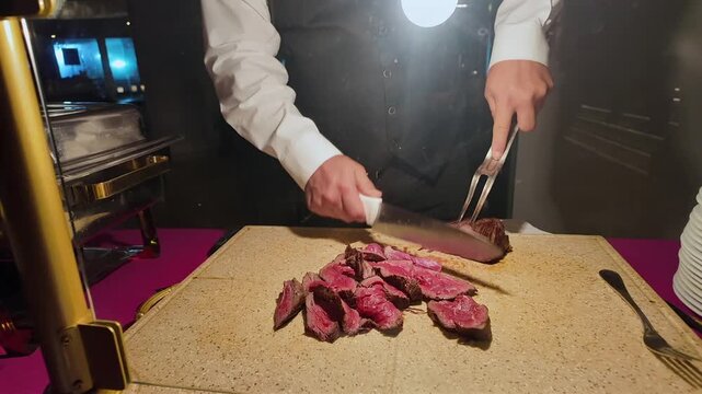 A chef cuts a tenderloin steak on a board at a luxury party buffet.