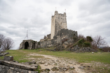 Anakopia fortress tower and stone walls on grassy hilltop under cloudy sky in Abkhazia. Image supports heritage tourism marketing, historical education projects and travel destination