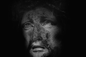 Extreme close-up of Jesus Christ stone statue emerging from darkness, intense gaze expressing faith, endurance, and deep spiritual mystery.