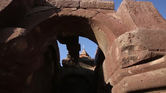 A string of decorative, colorful, triangular pennant flags with various unique illustrations gently flutters in the breeze against a blurred background of a city building and street lamps.

