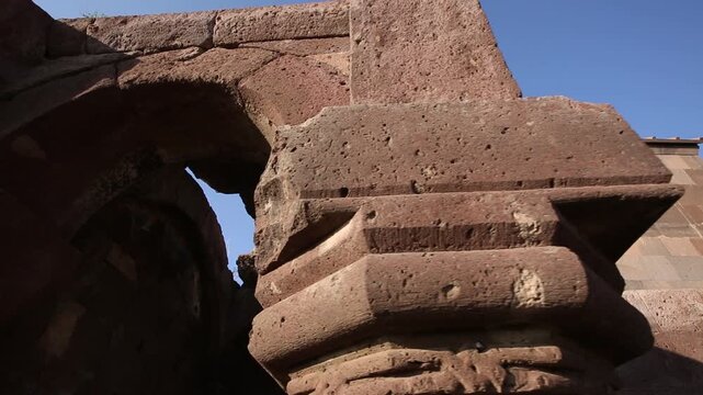 A string of decorative, colorful, triangular pennant flags with various unique illustrations gently flutters in the breeze against a blurred background of a city building and street lamps.

