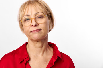 Fototapeta premium Portrait of confident mature woman with short hair and glasses wearing red blouse against white background. Concept of aging, confidence, wisdom, and natural beauty.