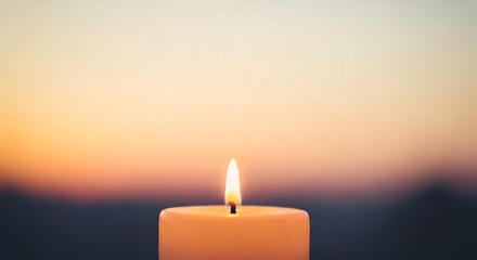 Close up shot of single lit candle flame burning softly against blurred sunset sky background at twilight creating peaceful mood for meditation prayer or memorial ritual