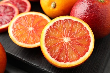 Fototapeta premium Whole and cut ripe Sicilian oranges on table, closeup