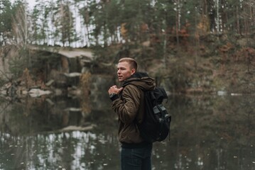 Young Man with Backpack by Forest Lake in Autumn