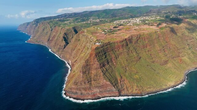 High volcanic cliffs with Ponta do Pargo lighthouse on the west coast of Madeira Island above the Atlantic Ocean, aerial view from drone