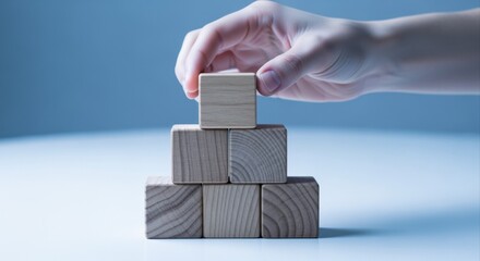 Building Blocks Pyramid: Hand Placing Wooden Cube on Top for Growth and Success Concept