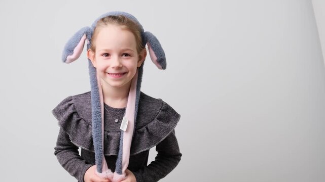 Charming Young Girl in Playful Bunny Hat with Moving Ears, Delightful and Joyful Child Portrait on White Background
