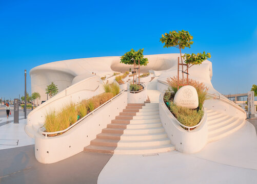 6 December 2025, Abu Dhabi, UAE: Contemporary TeamLab architecture with organic forms, winding stairs, strategically placed trees, and green plants framing a cafe entrance