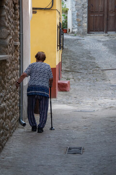 Senior woman walking with cane in old town, hervas, spain