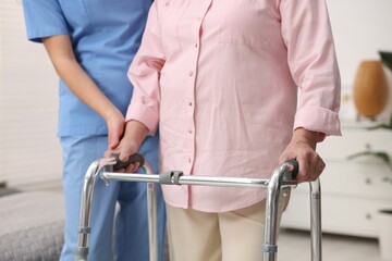 Care worker helping senior woman with walker indoors, closeup