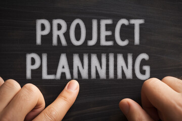 Hands point to the essential words "PROJECT PLANNING" on a chalkboard.