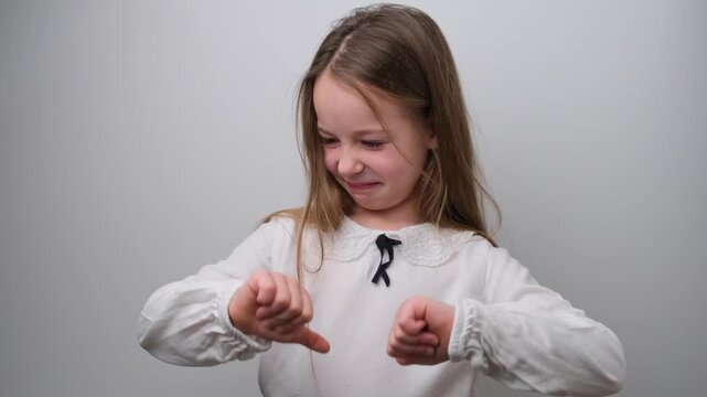 Disapproving Young Girl with Thumbs Down Gesture, Expressing Dislike or Poor Opinion on a White Background