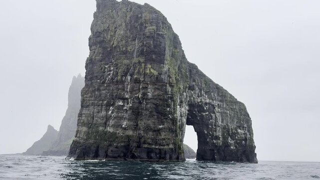 Green landscapes of the Faroe Islands. Drangarnir rock formation in the Atlantic ocean during a boat excursion, Vagar Island.