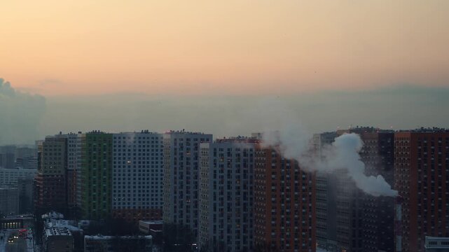 Urban skyline with new residential high-rise buildings and smoke rising from industrial areas, creating a morning haze. This image reflects environmental issues, air pollution, and urbanization in lar