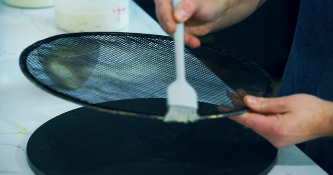 White oil brush spreading across pizza crisper - closeup shot