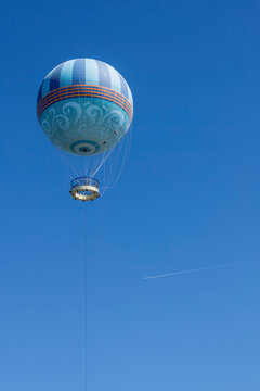 A vibrant hot air balloon floats peacefully over Kissimmee, Florida, offering breathtaking views of the clear blue sky.